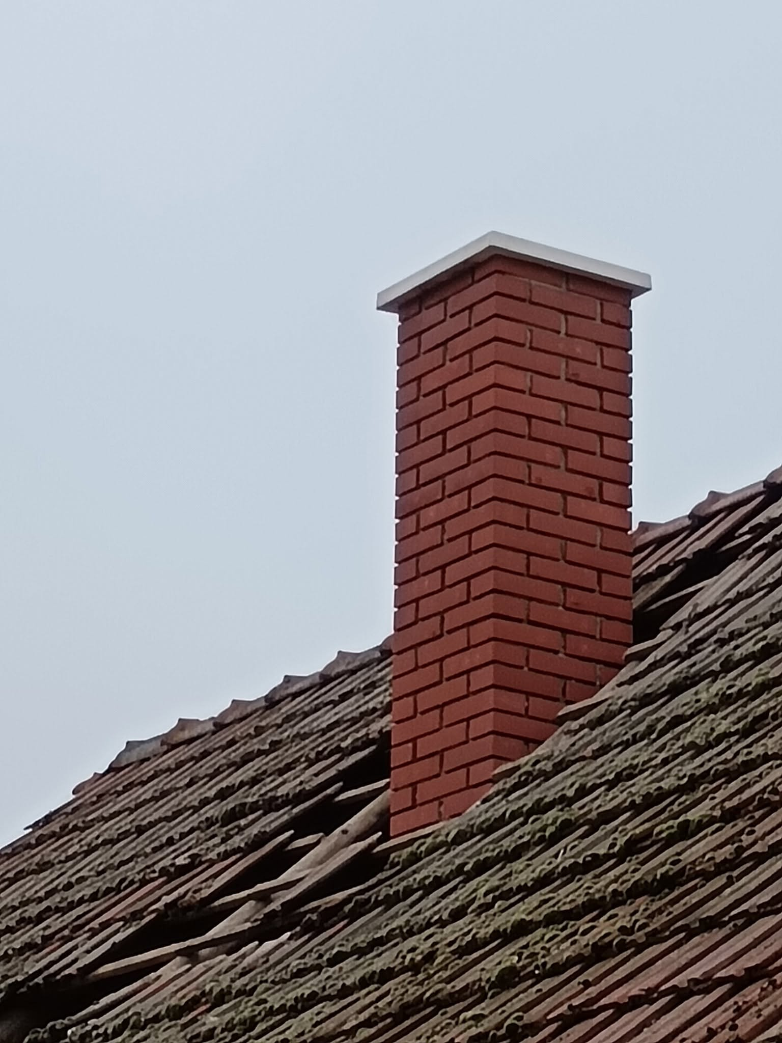 Újjáépített tégla kémény betonfedlappal a tetőn